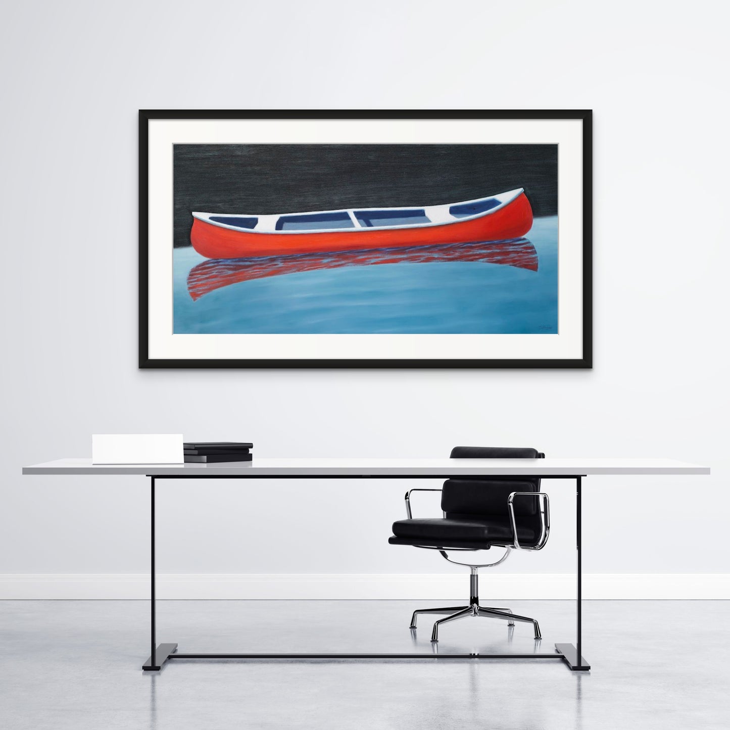 Canoe painting of a small red boat by Canadian artist Catherine McKinnon. The red canoe is floating on almost still blue water in the foreground and the background is pitch black. The giclee print is framed in black with white matting. It is mounted on a light gray wall above a contemporary desk and black chair.