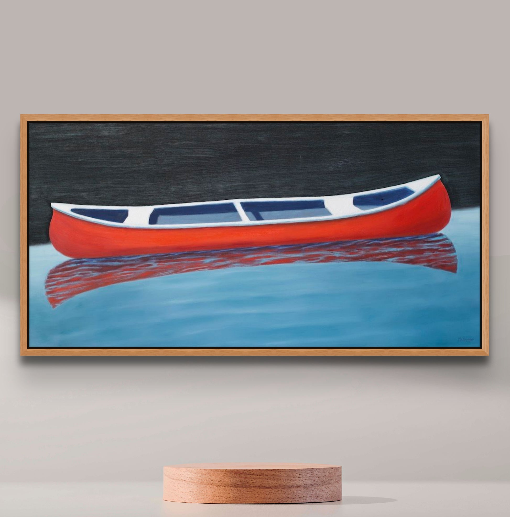 Canoe painting of a small red boat by Canadian artist Catherine McKinnon. The red canoe is floating on almost still blue water in the foreground and the background is pitch black. The giclee print is framed in cherry wood and is mounted on a medium gray wall.