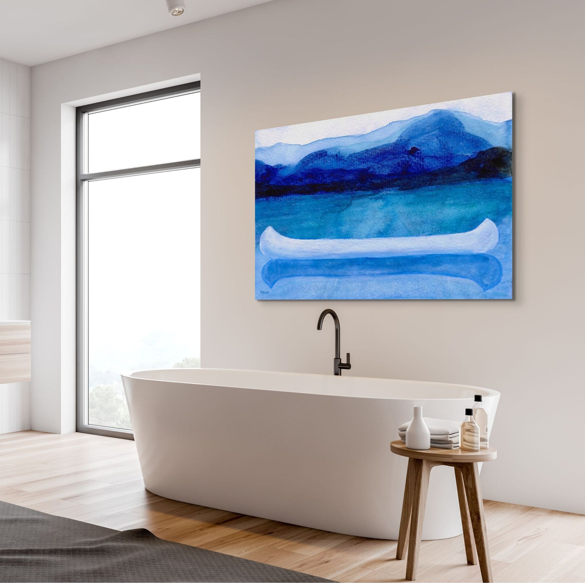 A work of canoeing art by Canadian artist Catherine McKinnon. The watercolor depicts a small white boat, a "canoe", on blue water with a dark blue distant shore and lighter blue distant moutains. The giclee print is frameless and is mounted on a light grey wall above a stylish, contemporary soaker tub.
