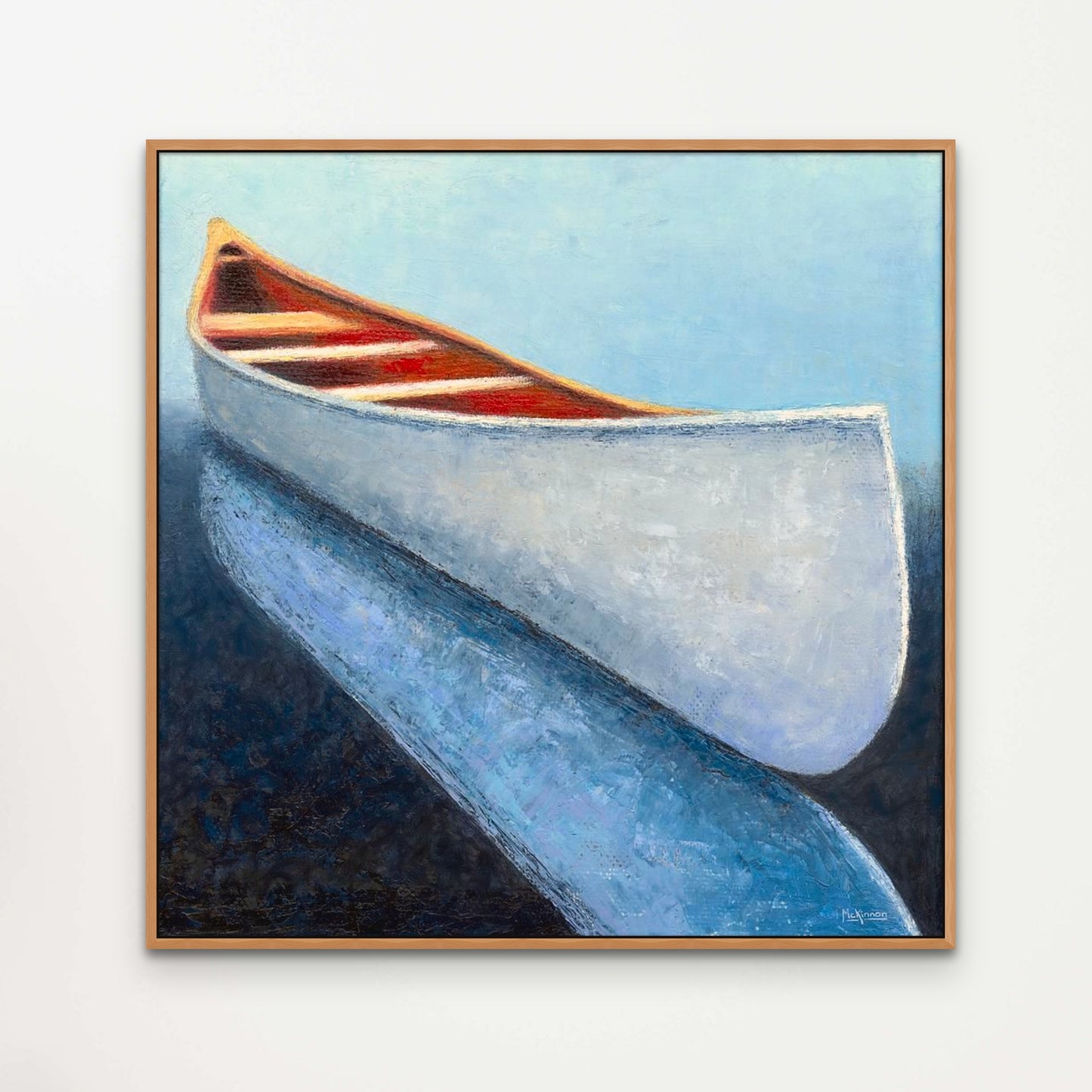 A coastal painting of a white canoe reflected in dark, navy blue water by Canadian artist Catherine McKinnon. This giclee print of the wall art is framed in cherry wood and mounted on a light grey wall as modern farmhouse style wall decor.